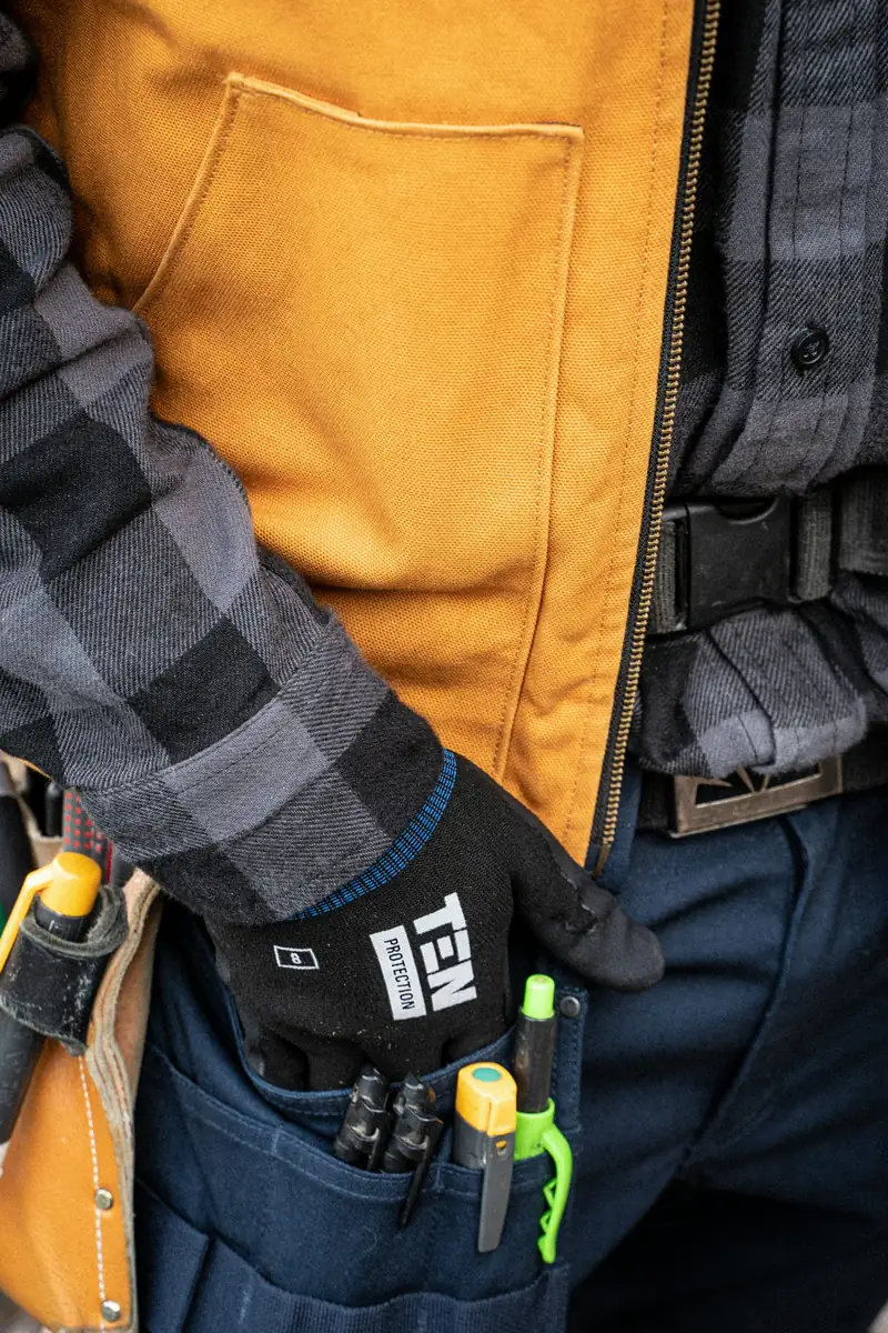 Work gloves and hand tools carried in an electrician’s workwear pockets.